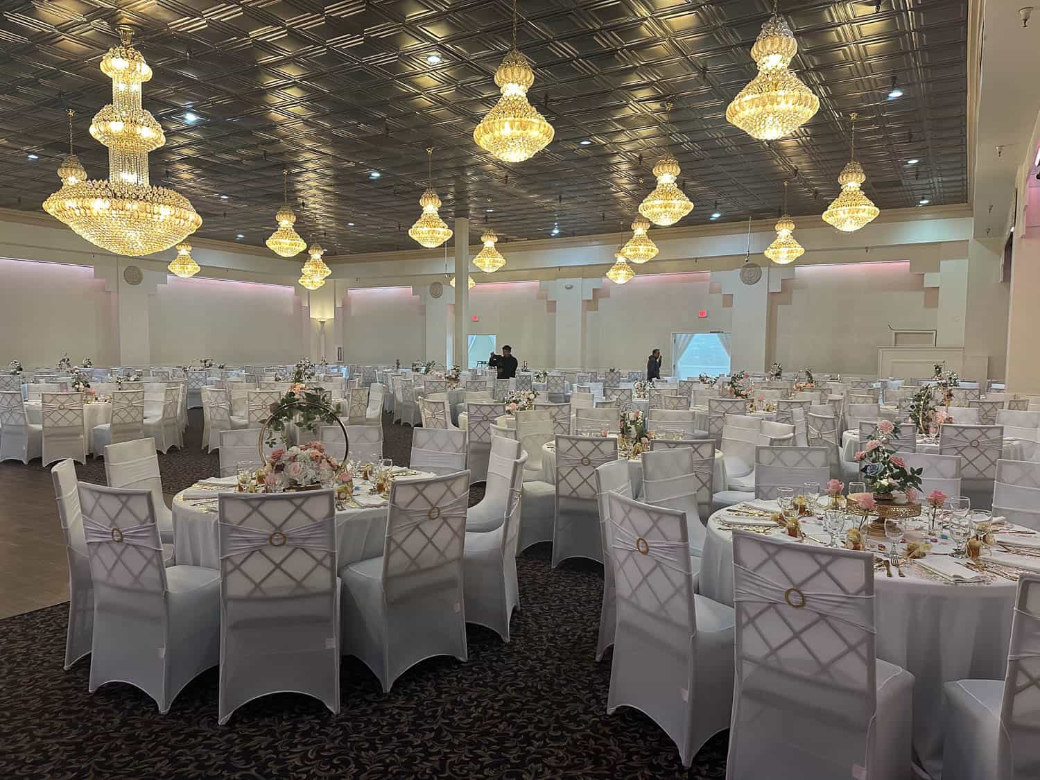 Elegant ballroom with round tables, floral centerpieces, and luxurious chandeliers for weddings and.