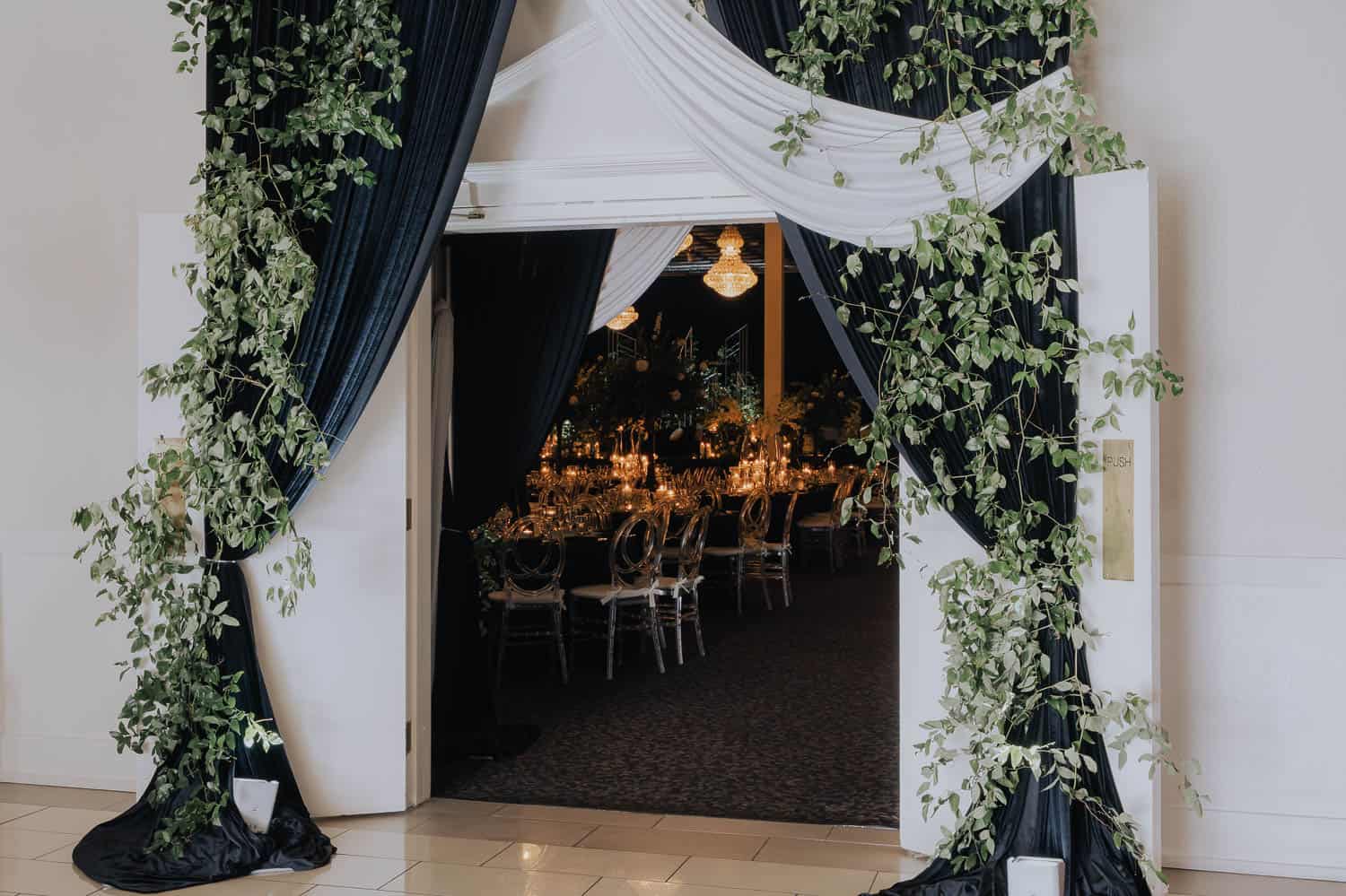 Beautiful decorated ballroom entrance with greenery and drapes for wedding receptions.