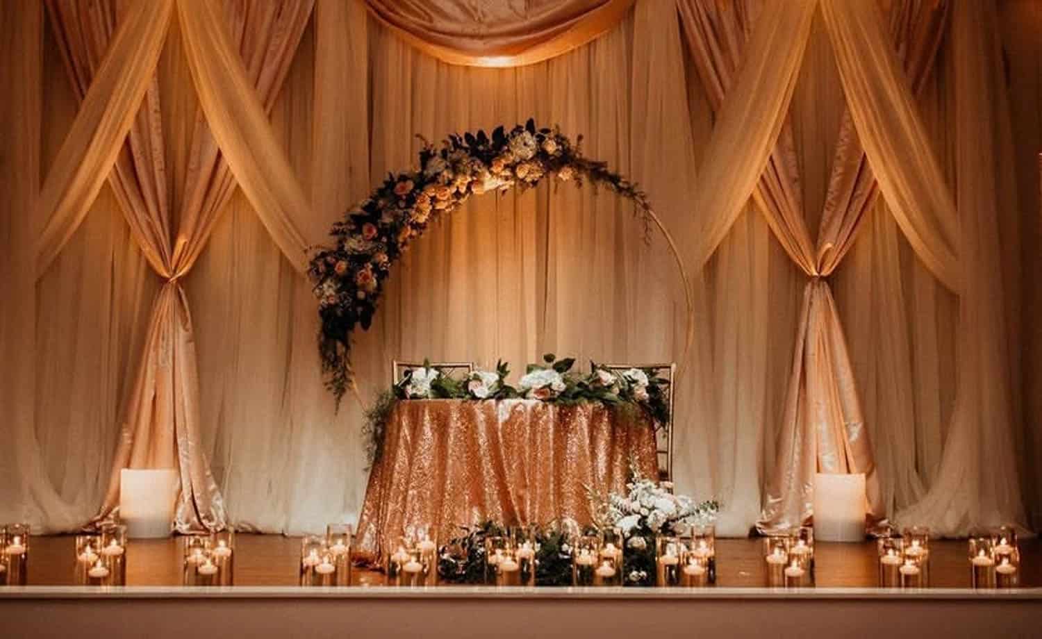 Elegant wedding reception backdrop with floral arch and draped curtains, perfect for ceremonies and.
