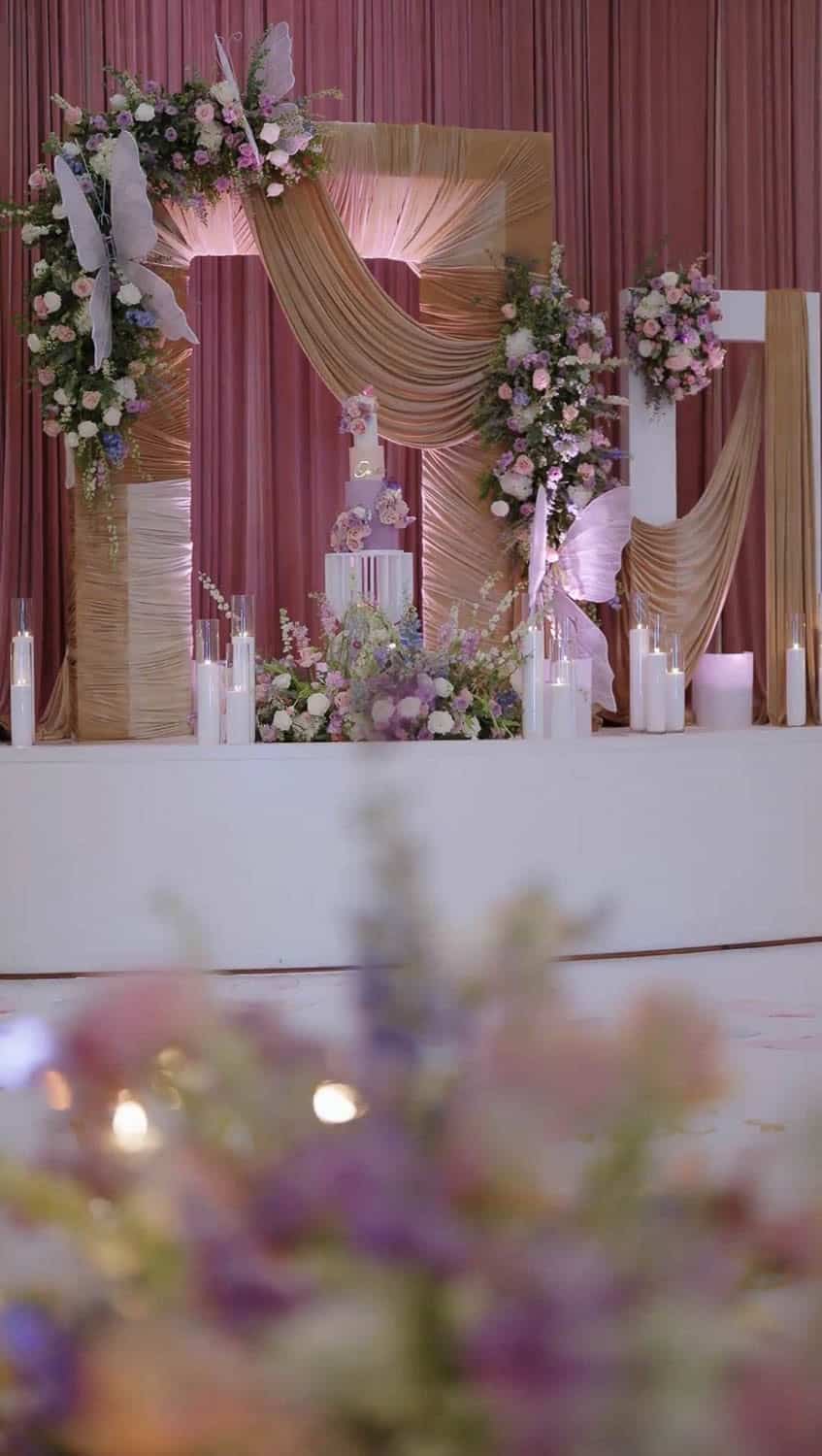 Beautiful floral wedding backdrop with pink and white flowers and flowing fabric.