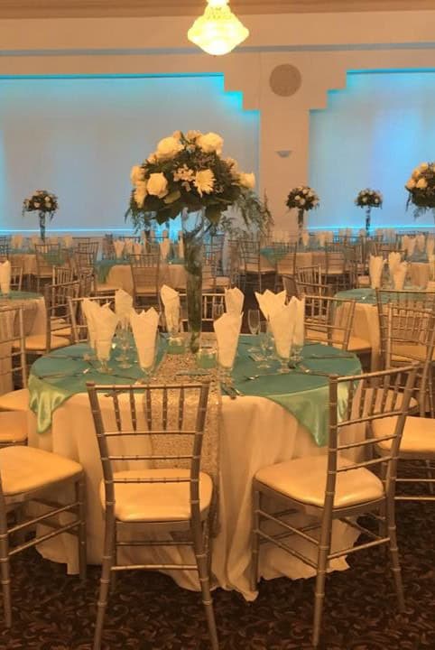 Ballroom event with round tables, floral centerpieces, and elegant decor.
